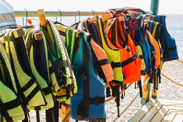 Group of Life jacket or life vest hanging on the wall of the boating station against sea coast