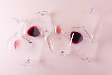 Pembe zemin üzerinde kırmızı, gül ve beyaz şarap bulunan çeşitli şarap kadehleri. Şarap tatma konsepti. Düz yatıyordu. Üst Manzara. Boşluğu kopyala