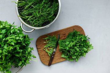 Gri ahşap masada domuz kesme üzerine doğranmış taze yeşil maydanoz ve dereotu veya rezene. Üst te. Kopya alanı. Hasat konsepti