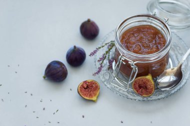 Gri ahşap arka plan üzerinde taze mor incir ile cam kavanozda ev yapımı incir reçeli. Yumuşak odak. Hasat zamanı veya sağlıklı gıda konsepti