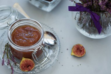 Gri ahşap arka plan üzerinde taze mor incir ile cam kavanozda ev yapımı incir reçeli. Yumuşak odak. Hasat zamanı veya sağlıklı gıda konsepti