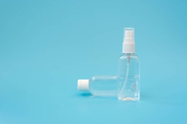 Antiseptik eşyalar. Mavi arka planda antiseptik el jeli ve sprey şişeleri. Grip, hastalık, pandemik konsept