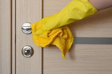 Kauçuk koruyucu eldivenli, kapı kollu bir kadın eli..