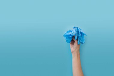 Mavi arka planda tıbbi eldiven tutuyor. Grip, hastalık, pandemik konsept