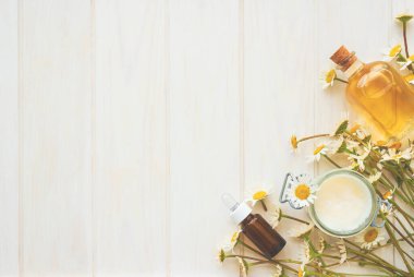 Papatya çiçekleri ve kozmetik şişeleri esaslı yağ ve beyaz ahşap arka planda özüt. Düz yatıyordu. Üst Manzara. Boşluğu kopyala