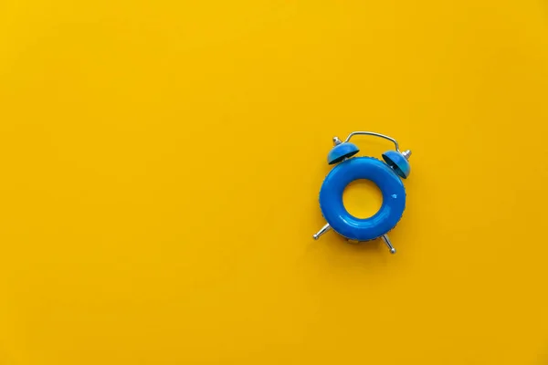 Wakacje Niebieski Budzik Jako Forma Pierścień Pływacki Żółtym Tle Widok — Zdjęcie stockowe