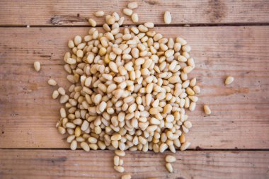 Ahşap arka planda bir yığın kabuklu çam fıstığı.