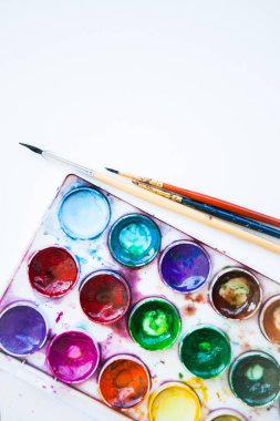 Beyaz arkaplanda çok renkli suluboya boya setleri