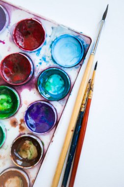 Beyaz arkaplanda çok renkli suluboya boya setleri