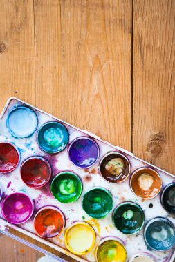 Ahşap arka planda çok renkli suluboya boya setleri
