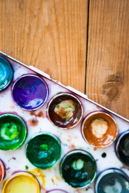 Ahşap arka planda çok renkli suluboya boya setleri