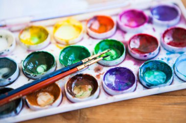 Ahşap arka planda çok renkli suluboya boya setleri