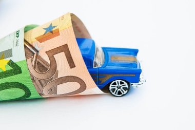 Banknotlara sarılı mavi oyuncak araba 50 ve 100 avro.