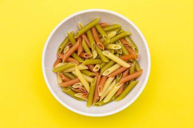 renkli makarna makarna parlak sarı arka plan üzerinde beyaz plaka