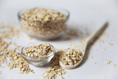 beyaz zemin üzerine kaşıkla şeffaf bir kase yulaf gevreği