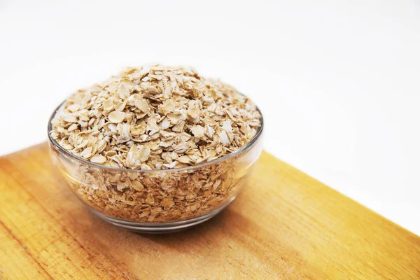 Oat flakes in a transparent bowl on cutting Board on white background Stock Picture