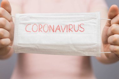 Roman Coronavirus - CORONAVIRUS yazılı cerrahi maske koruyucu maske. Çin Coronavirüs salgını. Maskeli kadın.