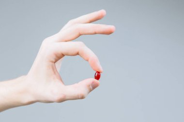 Elinde kırmızı haplarla gezen bir adam.