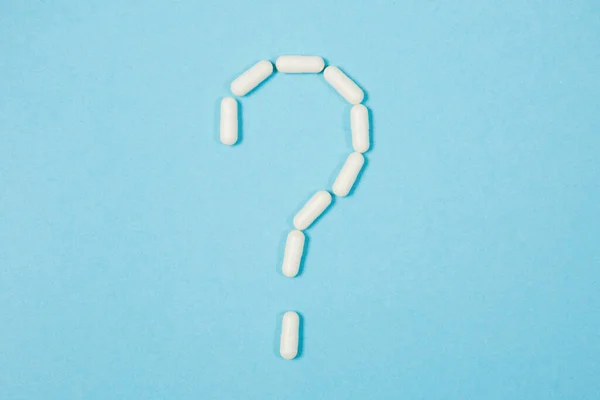 Mavi arka planda farklı haplar. Sağlık ve tıp. soru işareti