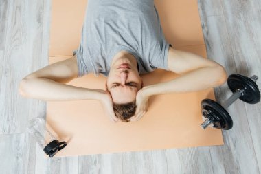 Genç adam spor yaparken sinirlenir. Yerde yatan adam.