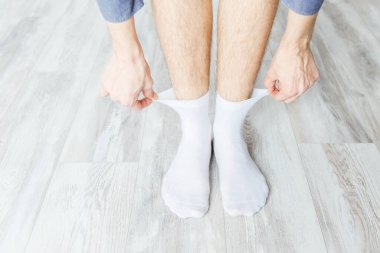 Beyaz çorapları gri ahşap bir odaya koyuyor.