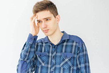 Açık gri arka planda mavi gömlekli üzgün genç adam. Depresyon, sorunlar ve stres.