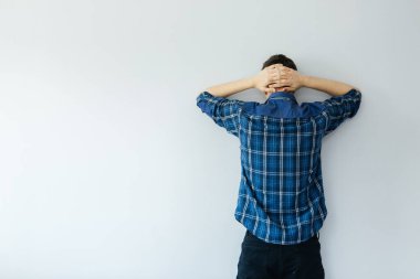 Mavi gömlekli genç bir adam duvara bakıyor. Depresyon, sorunlar ve stres
