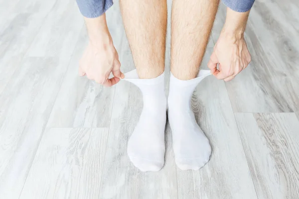 Beyaz çorapları gri ahşap bir odaya koyuyor.