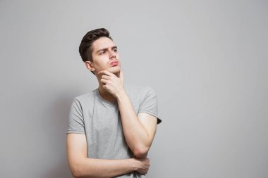 Gri tişörtlü, yüzünde duygular olan bir adam..