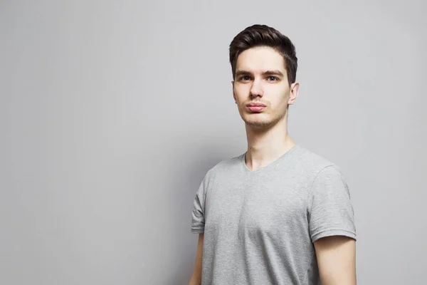 Gri tişörtlü, yüzünde duygular olan bir adam..