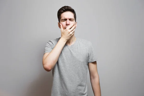 Gri tişörtlü, yüzünde duygular olan bir adam..