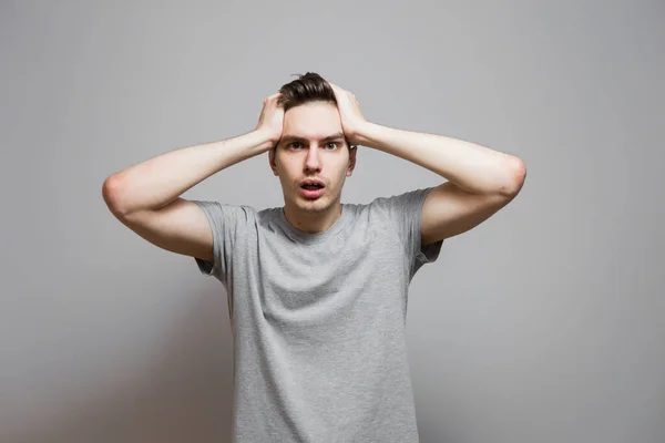 Gri tişörtlü, yüzünde duygular olan bir adam..