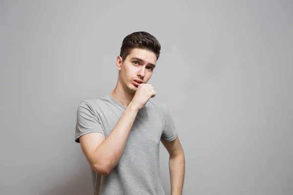 Gri tişörtlü, yüzünde duygular olan bir adam..