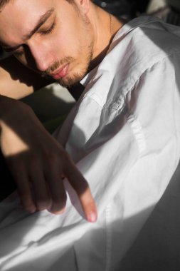 Beyaz gömlekli üzgün genç adam. Adam başını eğdi.