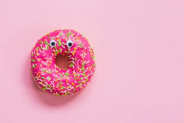 Pembe arka planda gözleri olan pembe bir çörek.