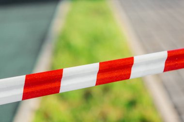 Bahçenin arka planında kırmızı ve beyaz koruyucu bant, evden çıkma yasağı. Evde kal.