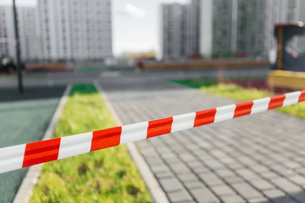 Bahçenin arka planında kırmızı ve beyaz koruyucu bant, evden çıkma yasağı. Evde kal.