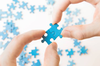 Mavi bulmaca elinde. Beyaz arka planda bulmaca parçasıyla el ele tutuşmak. Yapboz, iş bağlantısı, eğitim, toplum ve takım çalışmasına bağlanıyor