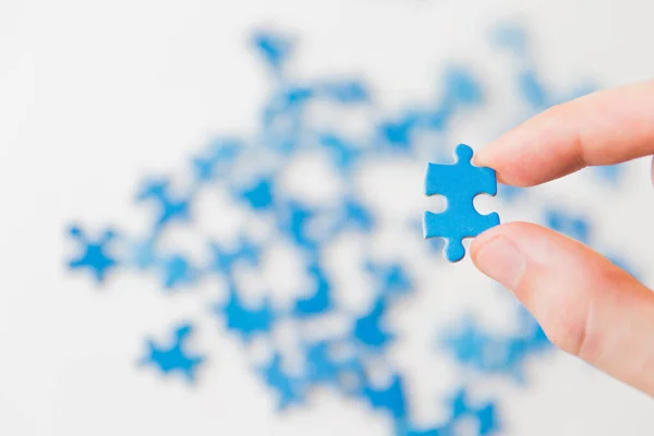 Mavi bulmaca elinde. Beyaz arka planda bulmaca parçasıyla el ele tutuşmak. Yapboz, iş bağlantısı, eğitim, toplum ve takım çalışmasına bağlanıyor