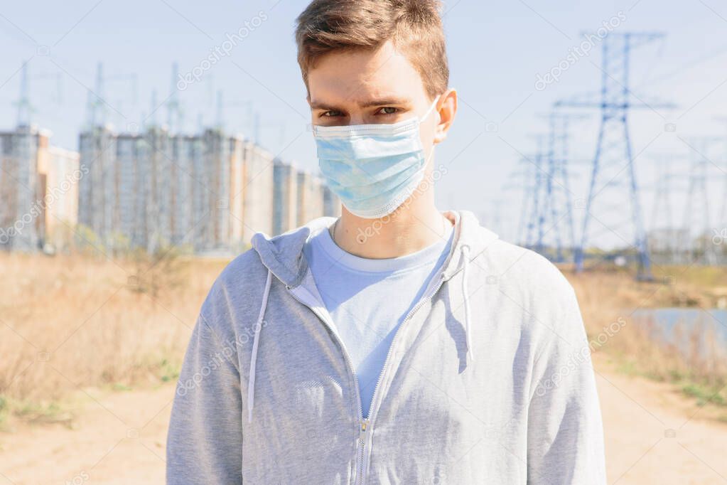Young guy in a medical mask on the street against the background of the city