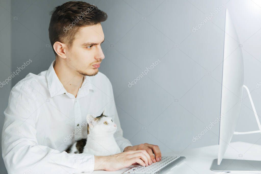 A man with a cat at home at a remote work at a computer