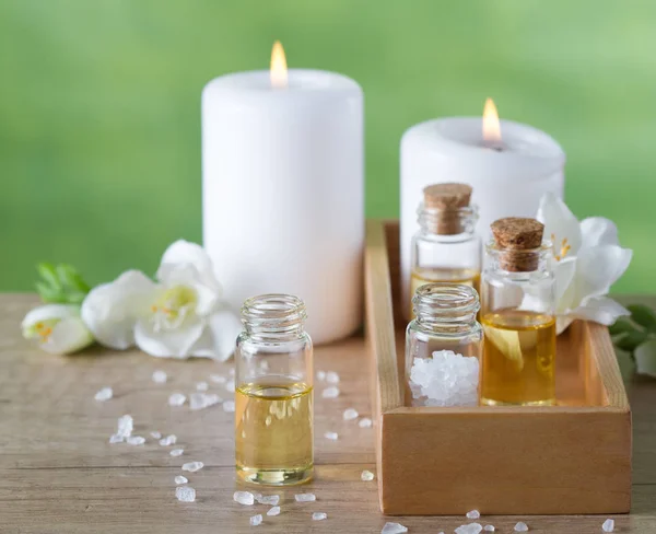 Aceites esenciales de aromaterapia en caja de madera, velas, flores y sal marina — Foto de Stock