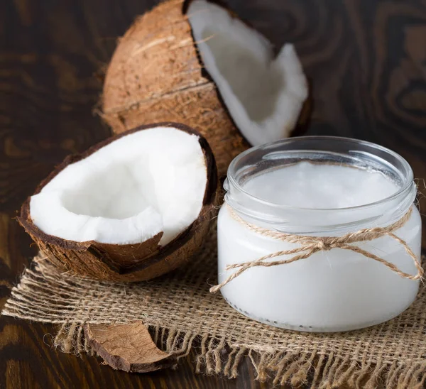 Coconut oil and fresh coconut on wooden table