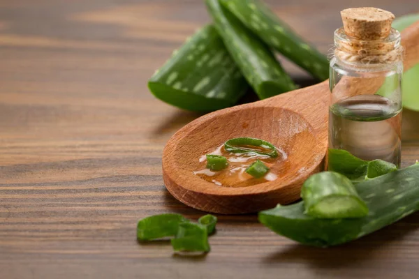 Zumo de aloe vera en cuchara de madera y hojas frescas de aloe vera — Foto de Stock