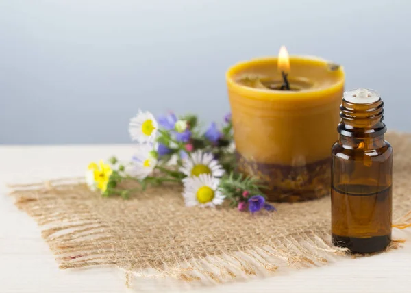 Essential oil and handmade beewax candle, flowers on wooden table — Stock Photo, Image