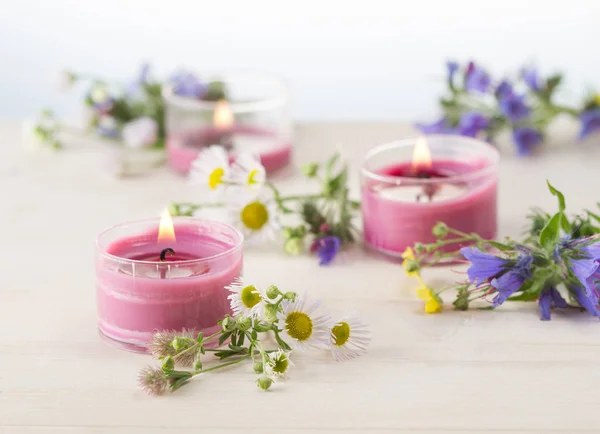 Burning candles and grass blossoms on white wooden table — Stock Photo, Image