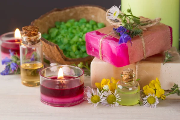 Aceites esenciales, velas encendidas, jabón hecho a mano, sal marina y flores de pasto. — Foto de Stock