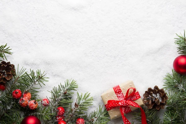 Рождественский фон с украшениями и подарочной коробкой на снегу — стоковое фото