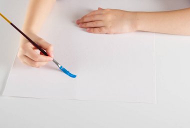 Beyaz arka plan üzerinde bir boya fırçası tutan çocuk el