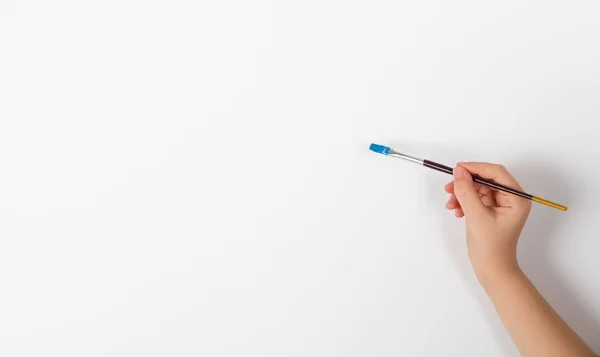 Criança mão segurando um pincel de pintura no fundo branco — Fotografia de Stock